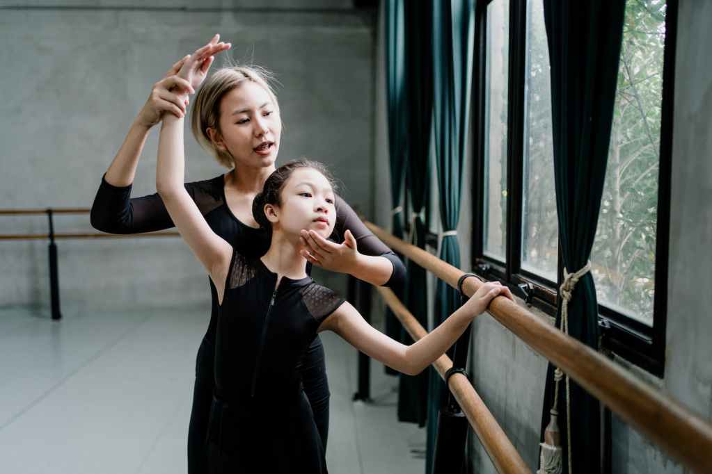asian ballet instructor explaining technique to girl
